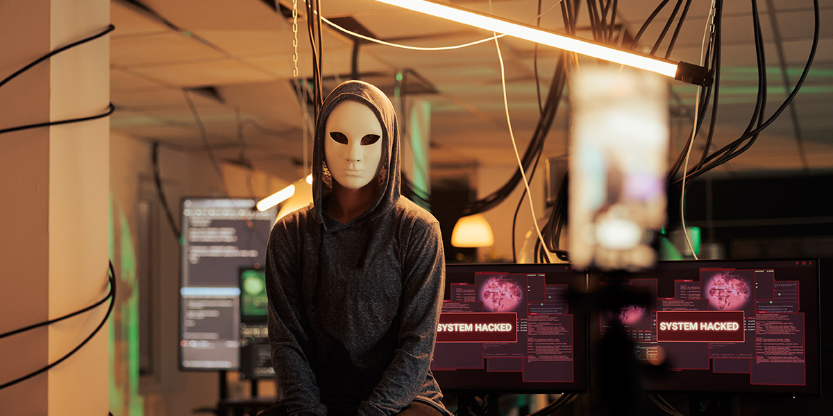 Ilustración digital que representa la dark web con una figura anónima frente a una pantalla iluminada en tonos azules y oscuros.