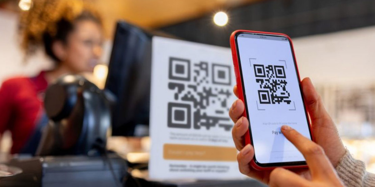 Persona escaneando un código QR en un establecimiento, representando el riesgo de códigos QR falsos y estafas digitales.